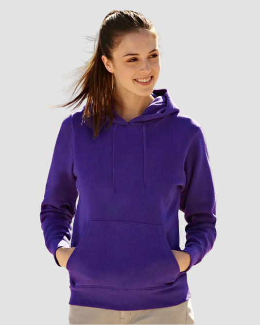 A woman wearing a solid purple pullover hoodie with drawstrings and a front kangaroo pocket, standing outdoors in a sunny, blurred field.