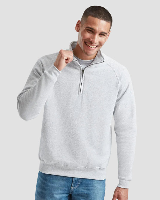 Man wearing a gray half-zip sweatshirt and blue jeans on a light gray background