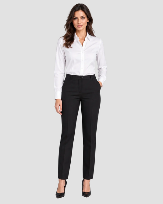 A woman modeling a white long-sleeve button-down shirt and black slim-fit trousers, paired with black pointed-toe heels, against a solid gray studio background.