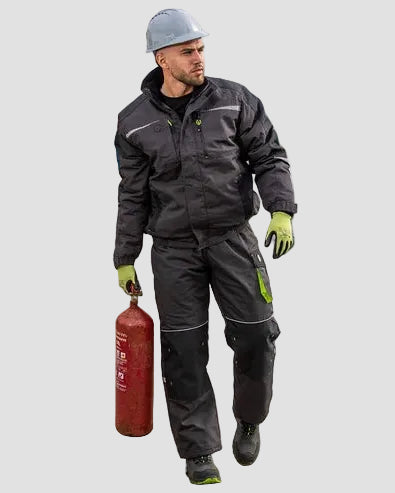 Man in safety gear holding a fire extinguisher on a dock with boats in the background